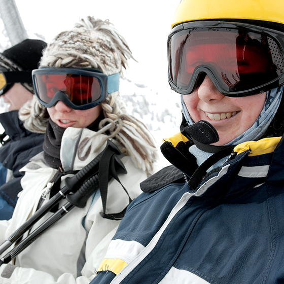 Student skiers smiling on ski lift